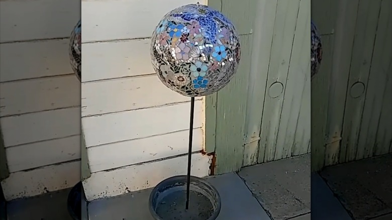 A large, round, shiny garden art piece