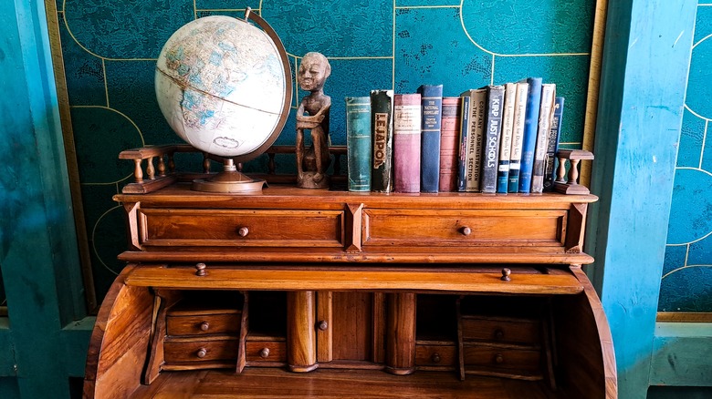 A vintage globe on wooden desk with a statue and books