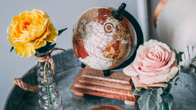 A small globe on a metal tray next to flowers
