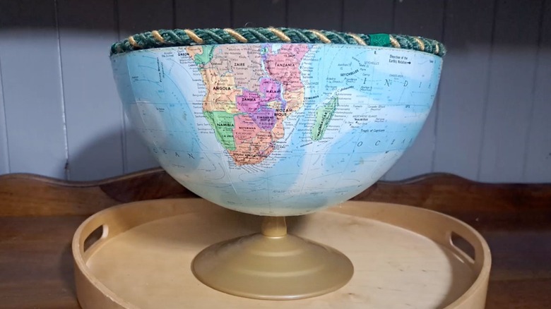 A globe bowl on a base with a decorative woven trim