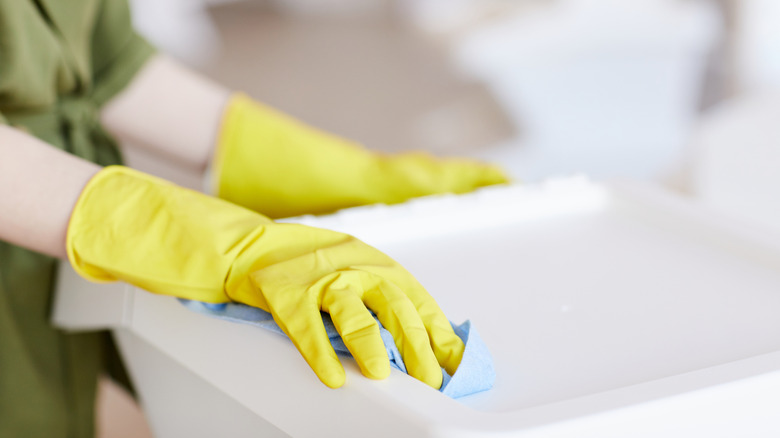 Person wiping out a trash can