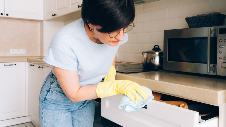 Woman wiping kitchen drawers