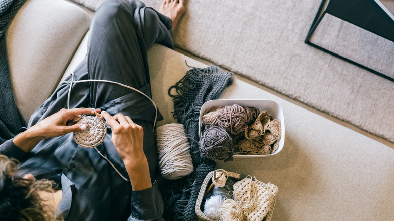 Person crocheting while sitting on a couch