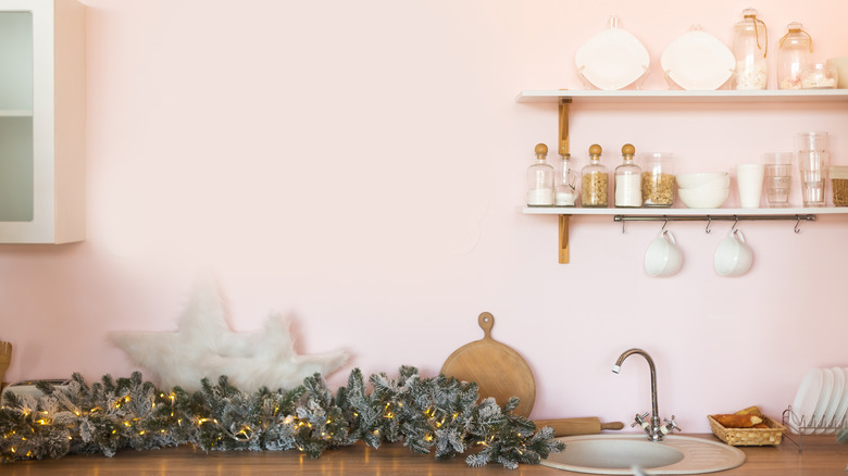 Pale pink walls in a kitchen with open shelves on the wall