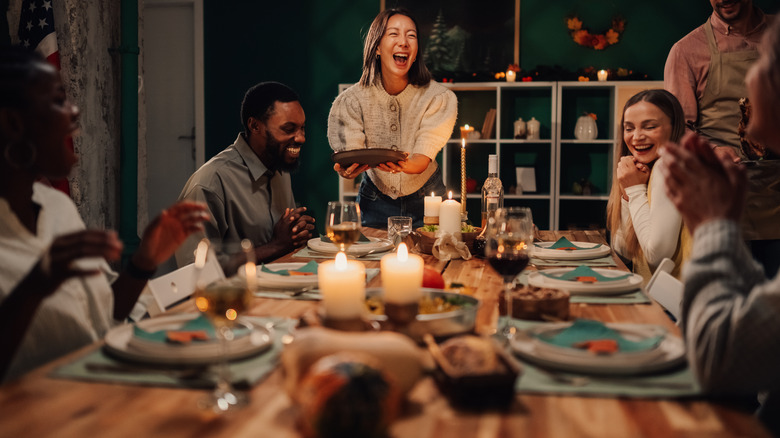 People enjoying a meal together at a table with dishes of food in the middle