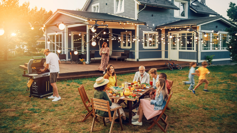 Family and friends enjoying a meal in a backyard while children play