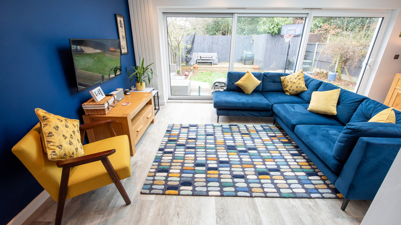 A blue and yellow styled living room with rug and tv.