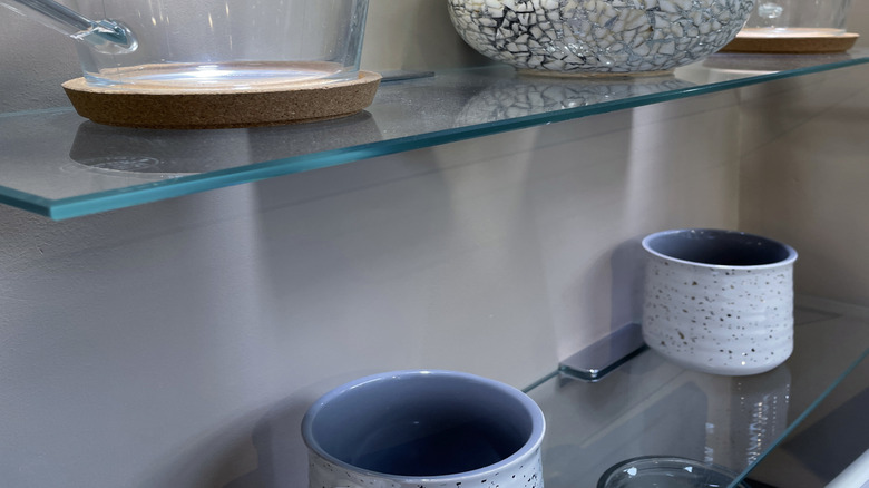 Floating glass shelves holding kitchen items.