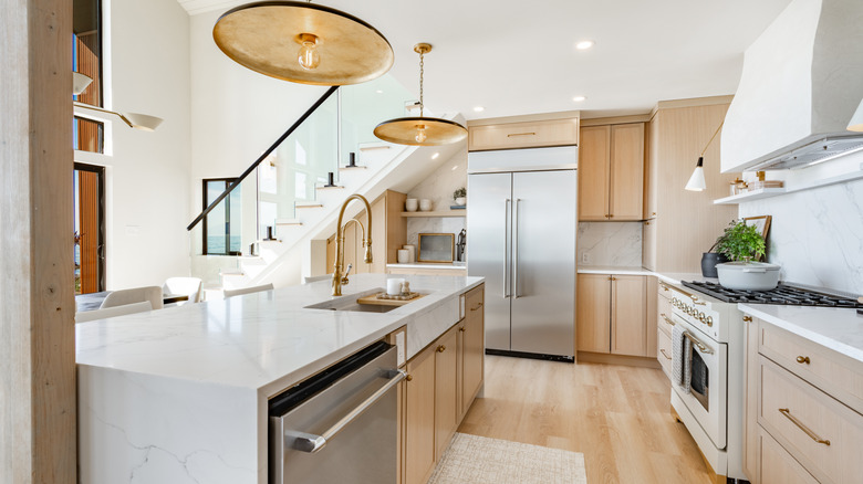 A modern kitchen with brass fixtures and lighting.