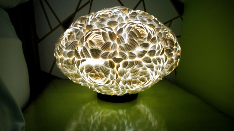An illuminated seashell lamp on nightstand.