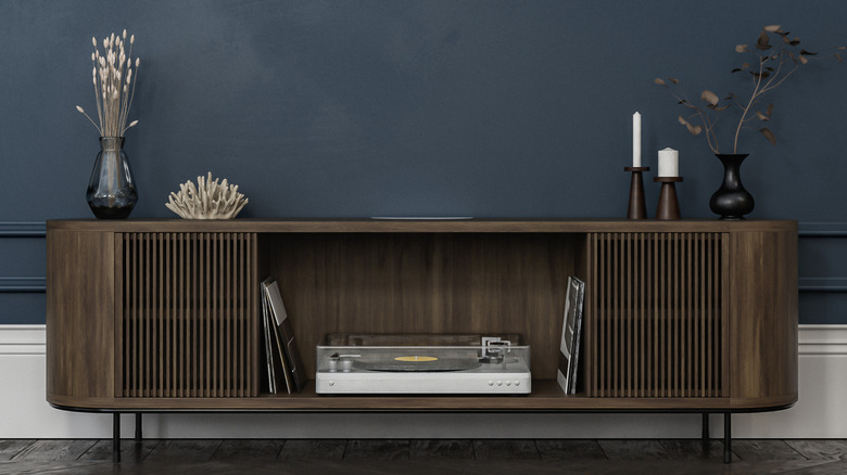 A dark wood console displayed on a charcoal accent wall.