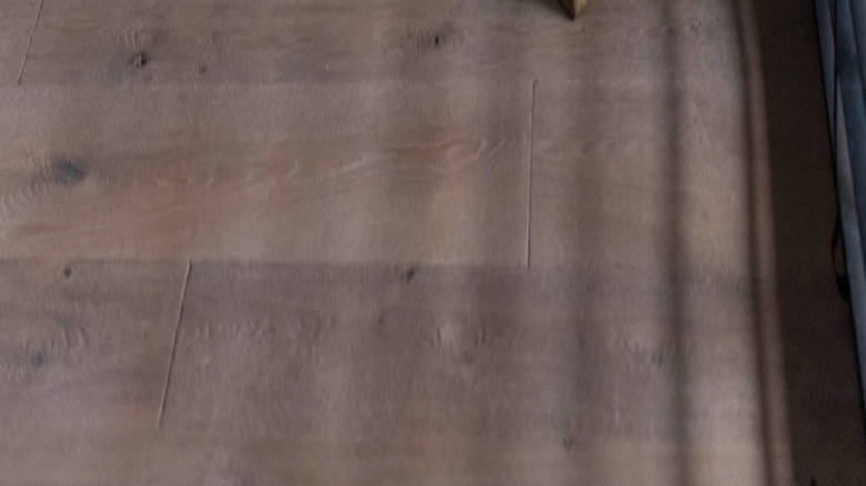 A dark wood bench in the corner of a room with deep blue walls and horizontal shades.