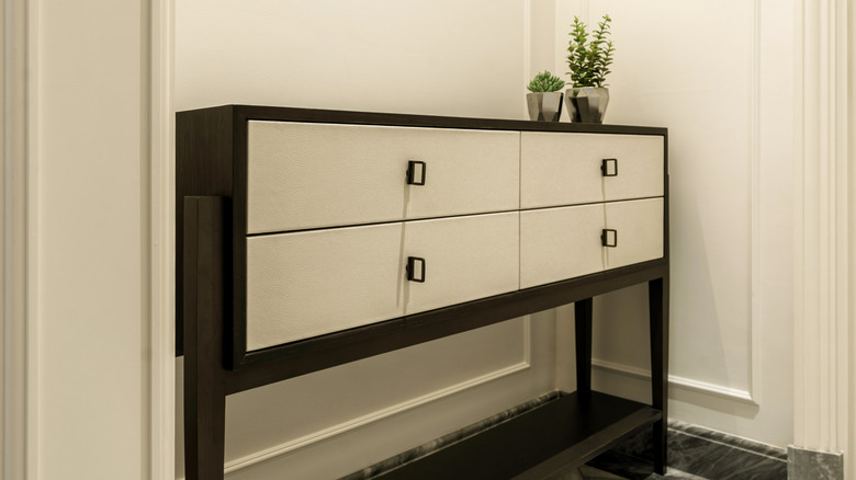 A cream and dark wood entryway console against eggshell walls.
