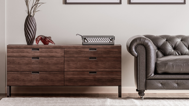 Dark wood console with other furniture in a ghost white room.