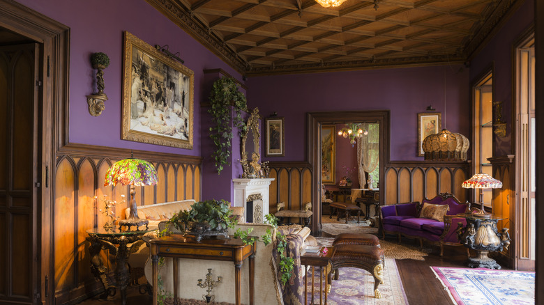Decadent living room with dark wood furniture and purple walls.
