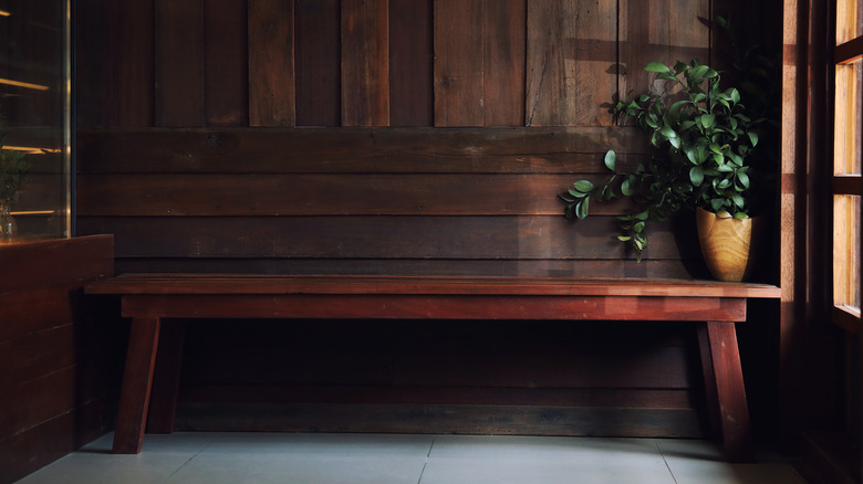 A dark wood bench and coffee table in a room with wood walls and wooden window frames.