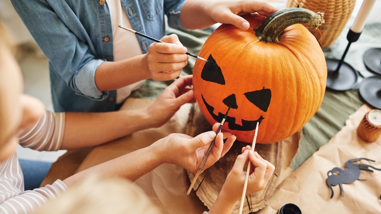 people painting face on pumpkin