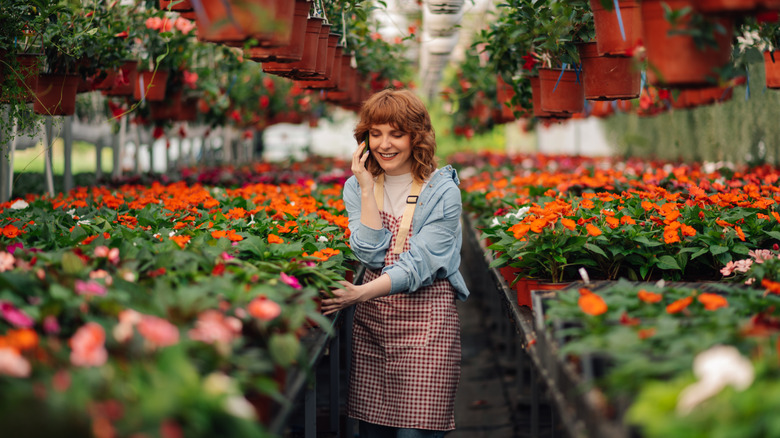 Smiling woman shopping alone while talking on the phone in a garden center