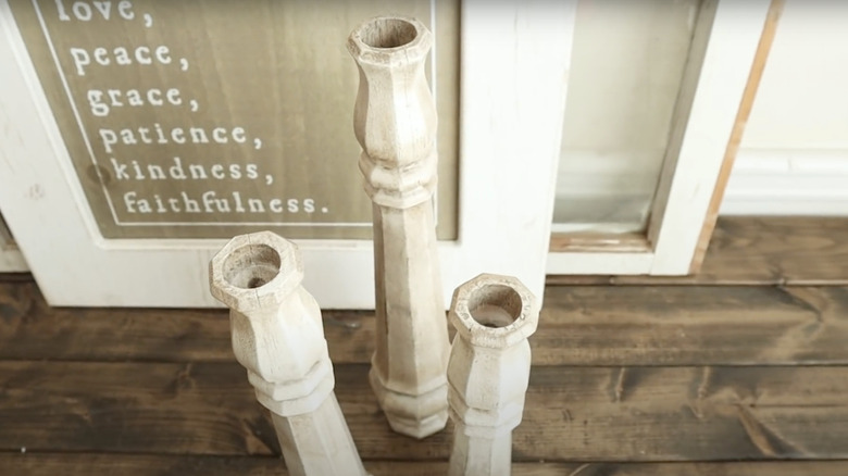 Candlestick holders made from deck railing spindles arranged on a mantle.