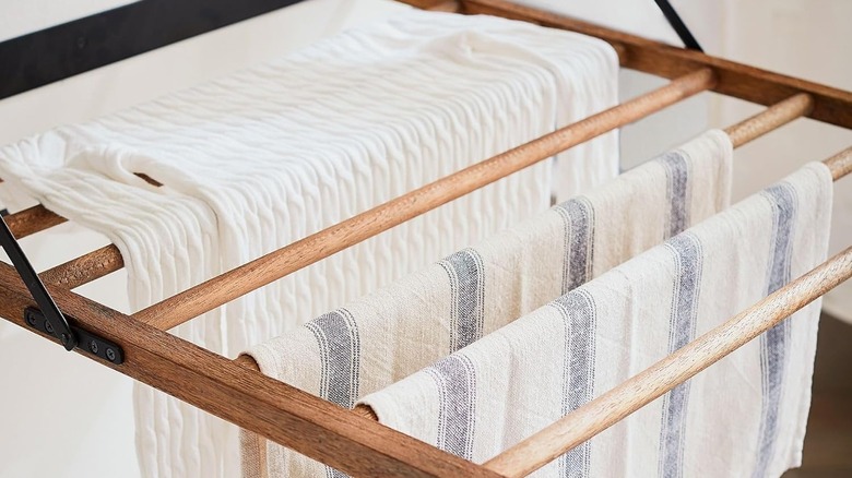 A brace is attached to old deck railings mounted to the wall as a drying rack for laundry.