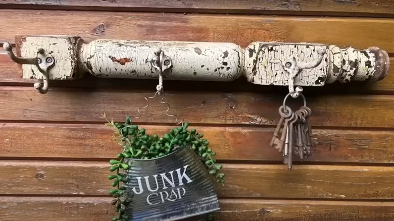 A succulent planted in a tin can hangs from a decorative wall hook made from a porch spindle.