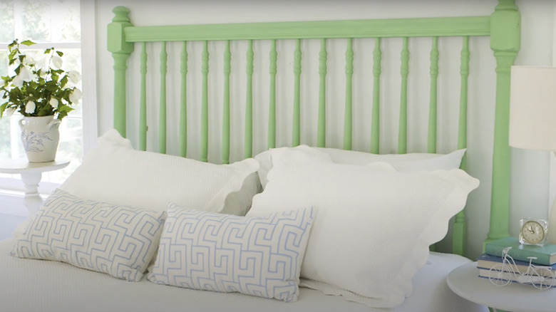 A green painted headboard made from a section of wooden deck railing.