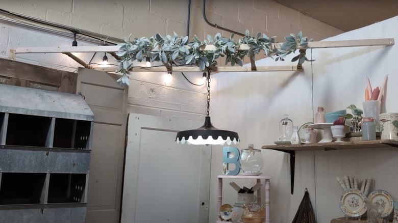 An old section of porch railing is fitted to the ceiling and a light and faux wreath is hung from it.