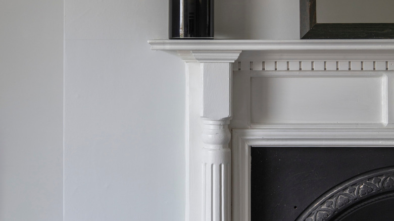 A white-painted wooden fireplace surround features turned spindles on each side.