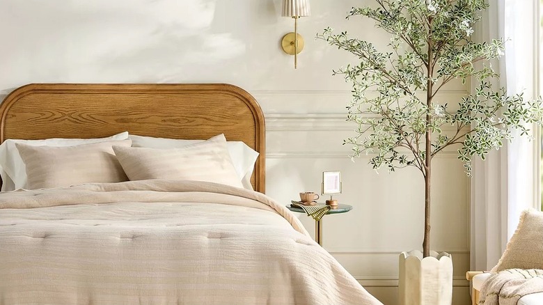 An artificial tree in a corner of a bedroom