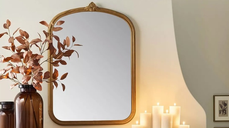 Framed mirror on a wall with candles and other decor items around it