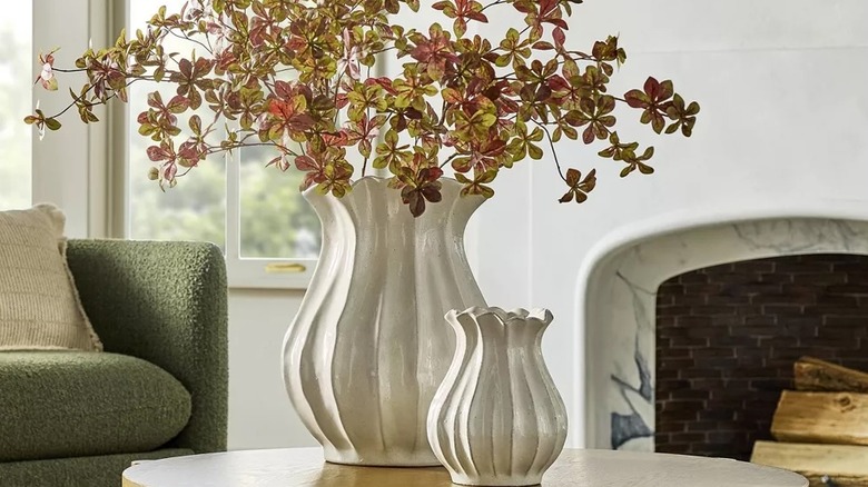 White sculptured vases on a table filled with faux stems