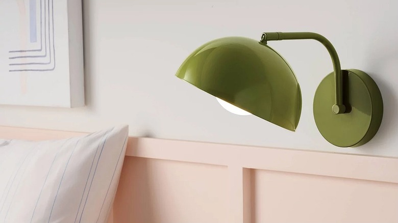 Green wall sconce near a bed