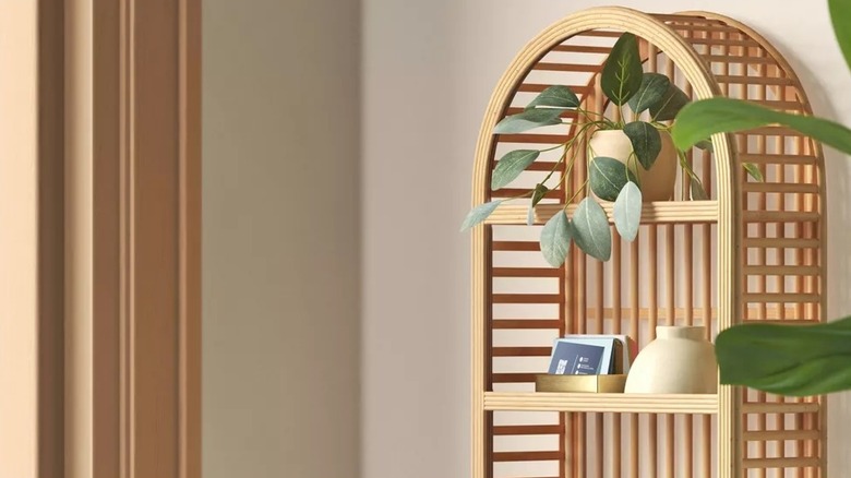 Rattan shelf hanging on a wall displaying ornaments and plants