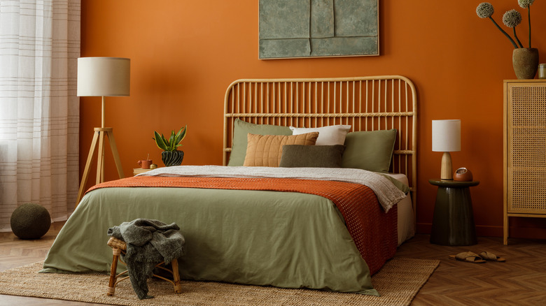 Bed with a rattan headboard against an orange bedroom wall