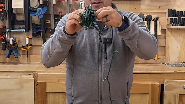 Hands wrapping Christmas string lights into a ball