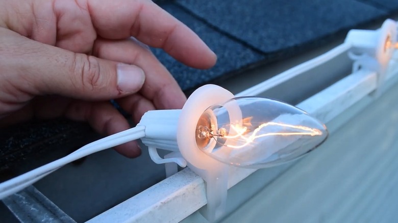 A lit bulb looped through a white tuff clip