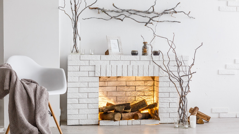 A white brick fireplace with faux logs and lights in the hearth.