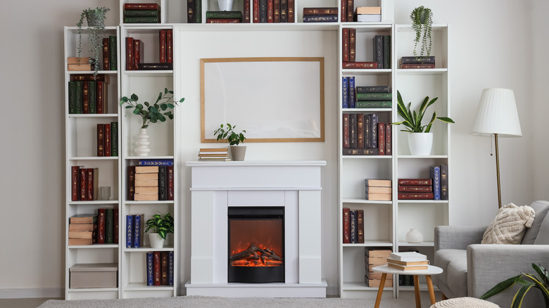 A small electric fireplace with skinny bookcases framing the space.