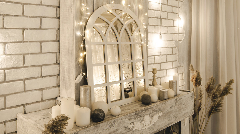 A winter themed fireplace with fairy lights strung up above the mantel.