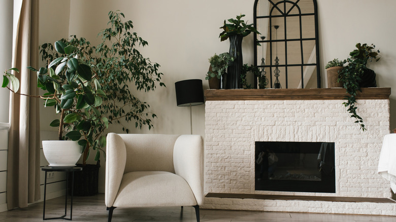 A living room with black and white furniture and a large mirror sitting on the mantel of a brick fireplace.