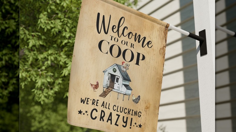 A funny and rustic garden flag placed over a coop