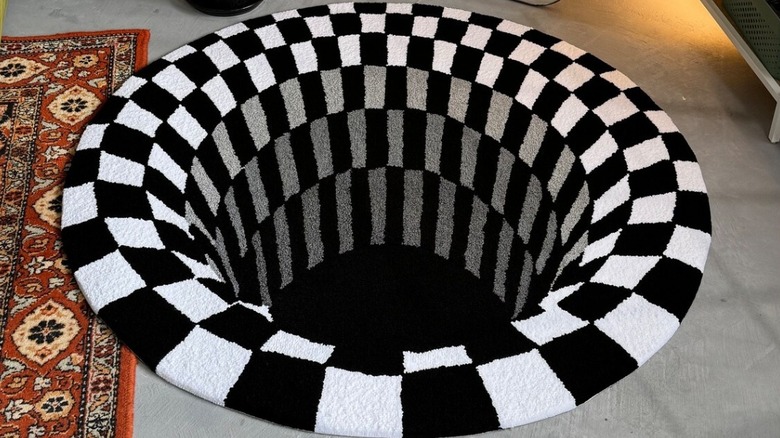 A 3D black and white optical illusion rug on a floor