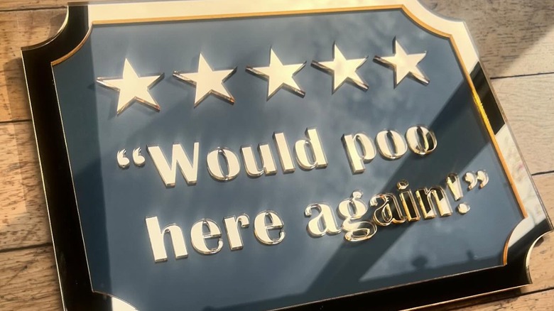 A sign declaring someone would poo on a wooden deck again