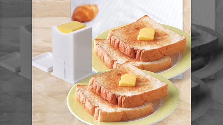 A butter dispenser stands beside two plates of toast topped with butter.