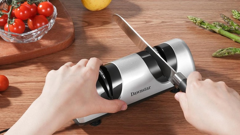 A person sharpens a knife using an electric knife sharpener.