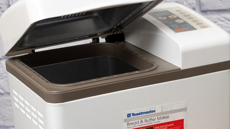 A bread maker in front of a white brick kitchen wall.