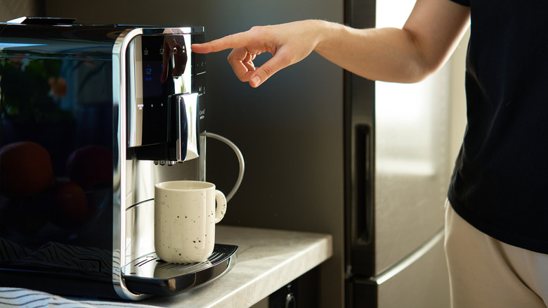 A woman pressing a button on a coffee machine.
