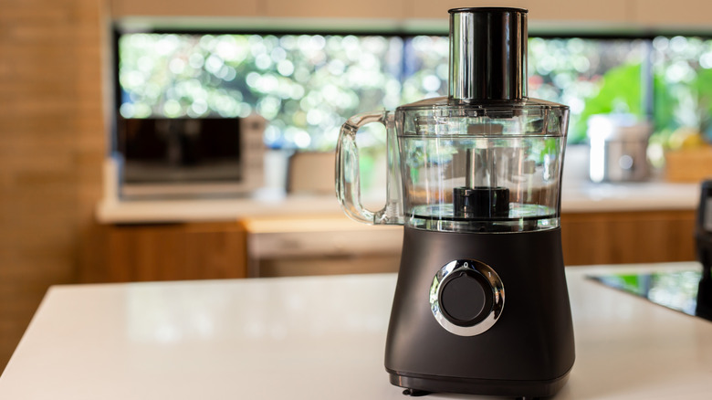 A black food processor standing on a kitchen counter.