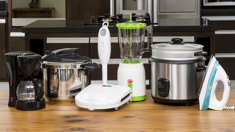 A range of essential small kitchen appliances on a pine tabletop