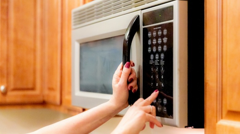 A person setting cook time on an OTR microwave.